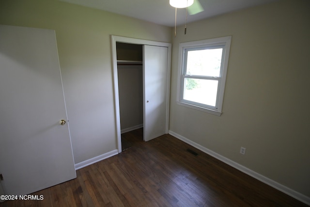 unfurnished bedroom with ceiling fan, a closet, and dark wood-type flooring