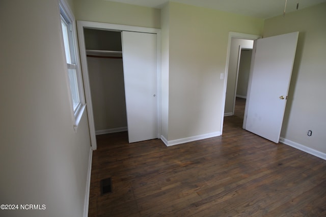 unfurnished bedroom with dark hardwood / wood-style floors and a closet