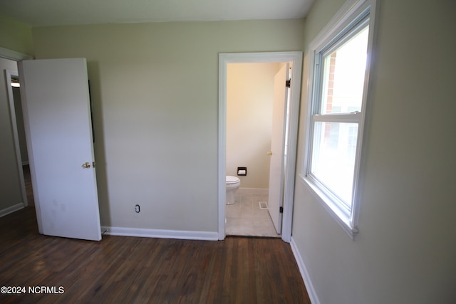 unfurnished bedroom featuring ensuite bath and hardwood / wood-style floors