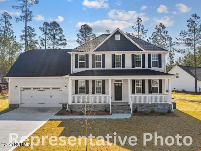 view of front of home with driveway, covered porch, a garage, and a front yard