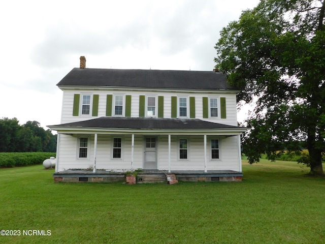 view of front of property featuring a porch, a chimney, and a front lawn