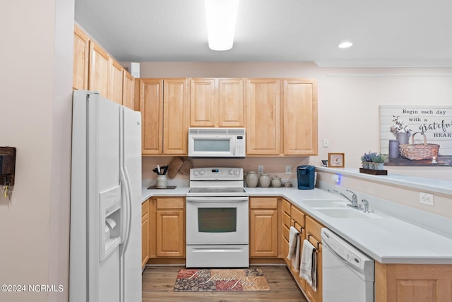 kitchen featuring white appliances, a sink, a peninsula, and light brown cabinetry