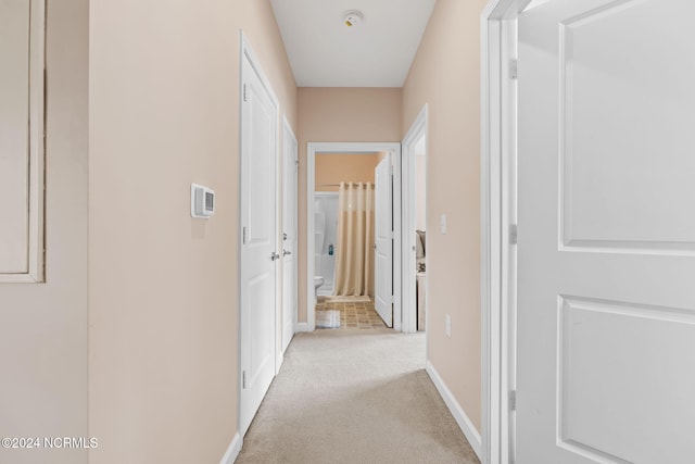 corridor featuring light carpet and baseboards