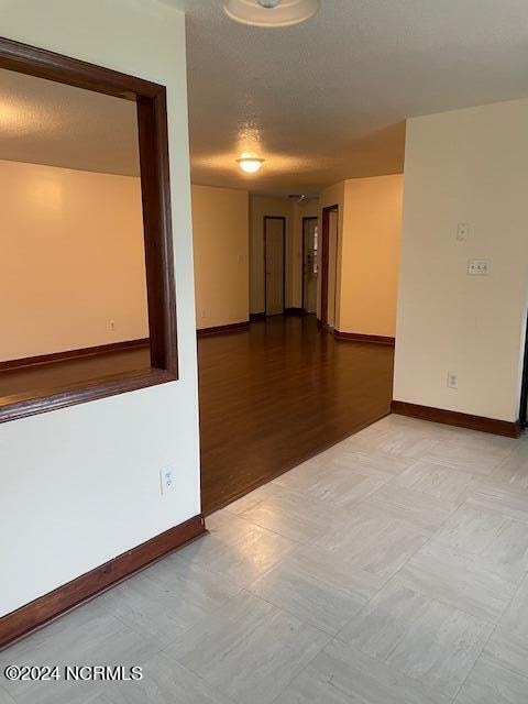 empty room featuring a textured ceiling and light hardwood / wood-style flooring