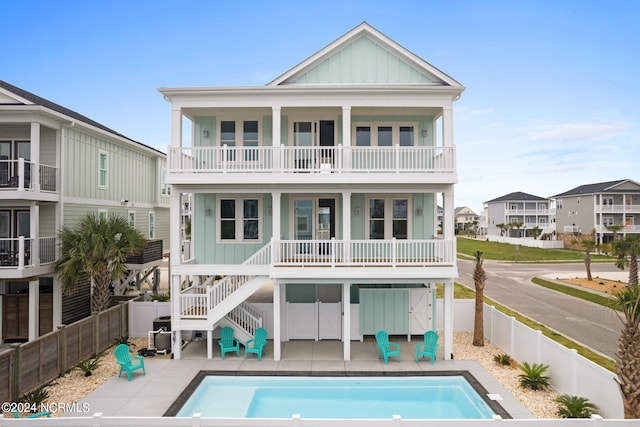 back of property featuring a fenced in pool, a patio area, and a balcony