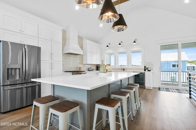 kitchen featuring wine cooler, white cabinets, a kitchen island, premium range hood, and stainless steel appliances