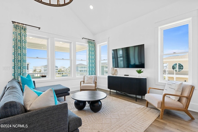 living room with light hardwood / wood-style flooring, lofted ceiling, and plenty of natural light