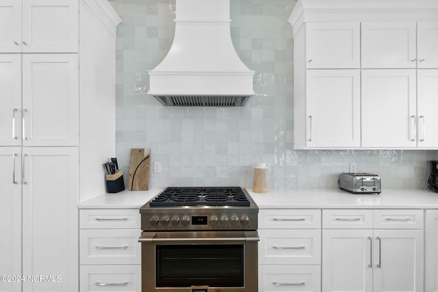 kitchen with custom exhaust hood, decorative backsplash, white cabinets, and high end stainless steel range oven