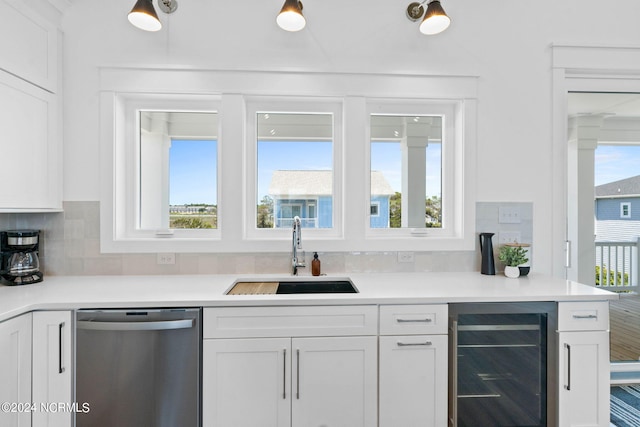 kitchen featuring stainless steel dishwasher, sink, white cabinetry, and beverage cooler