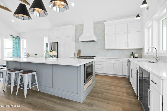 kitchen featuring appliances with stainless steel finishes, sink, a center island, custom exhaust hood, and white cabinets