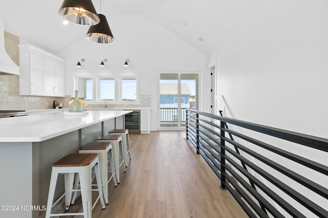 kitchen featuring decorative backsplash, white cabinets, wine cooler, wood-type flooring, and pendant lighting