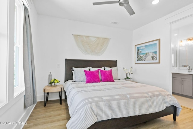 bedroom featuring ensuite bathroom, sink, light hardwood / wood-style floors, and ceiling fan