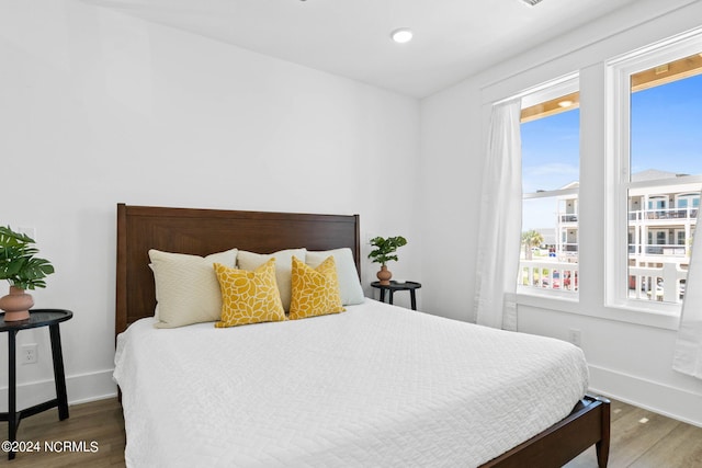 bedroom featuring multiple windows and dark hardwood / wood-style flooring