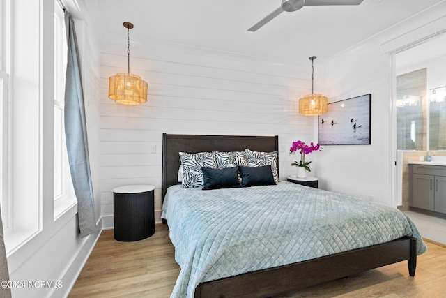 bedroom with light hardwood / wood-style floors, multiple windows, and ensuite bath