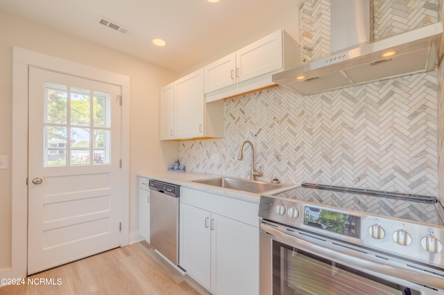 kitchen with appliances with stainless steel finishes, backsplash, light hardwood / wood-style floors, sink, and wall chimney range hood