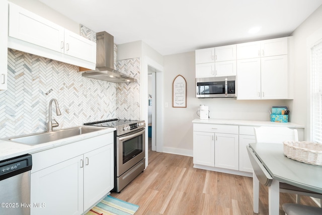 kitchen with white cabinetry, appliances with stainless steel finishes, sink, and wall chimney exhaust hood