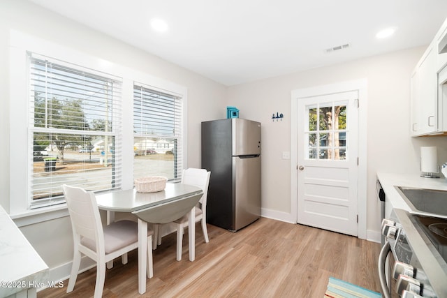 kitchen with stainless steel appliances, light hardwood / wood-style flooring, and white cabinets