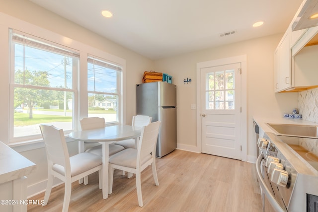 dining room with sink, plenty of natural light, and light hardwood / wood-style flooring