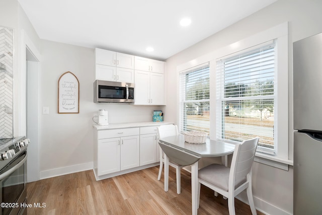 kitchen with white cabinetry, stainless steel appliances, and light wood-type flooring