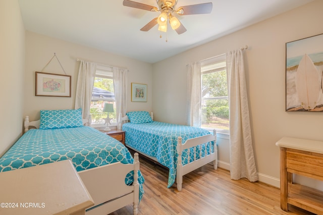 bedroom featuring ceiling fan, light hardwood / wood-style floors, and multiple windows