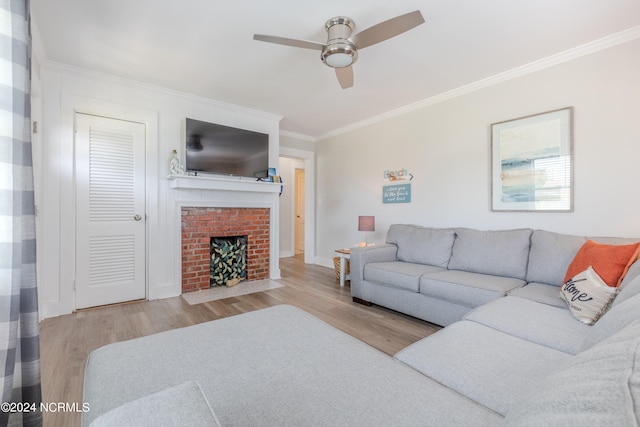 living room featuring light hardwood / wood-style floors, ornamental molding, ceiling fan, and a brick fireplace