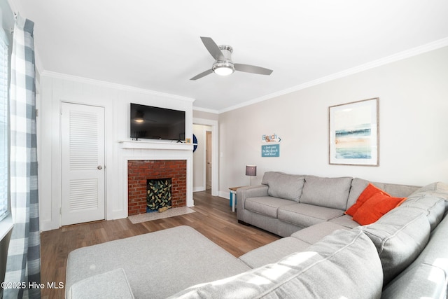 living room with crown molding, a brick fireplace, ceiling fan, and light hardwood / wood-style flooring