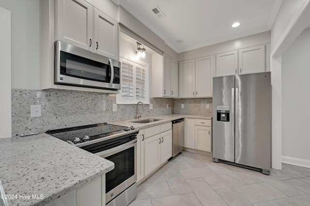 kitchen featuring stainless steel appliances, backsplash, light stone countertops, sink, and white cabinets