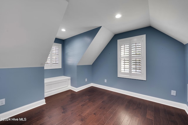 additional living space with hardwood / wood-style floors and vaulted ceiling