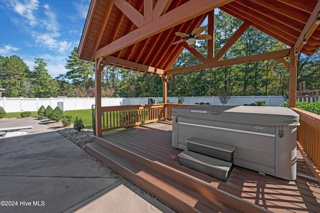 wooden terrace featuring ceiling fan, a gazebo, and a hot tub