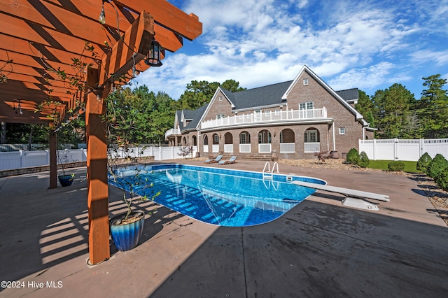 view of swimming pool with a diving board and a patio