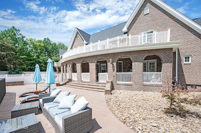 rear view of house with a balcony, outdoor lounge area, and a patio area