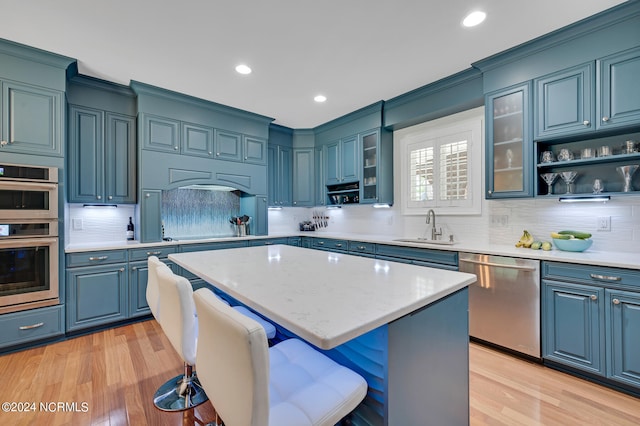 kitchen featuring sink, a kitchen island, a breakfast bar, light wood-type flooring, and appliances with stainless steel finishes