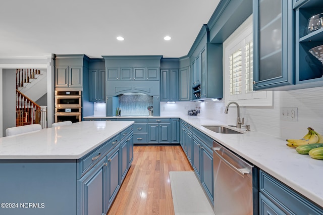 kitchen with stainless steel appliances, light hardwood / wood-style floors, sink, blue cabinetry, and a center island