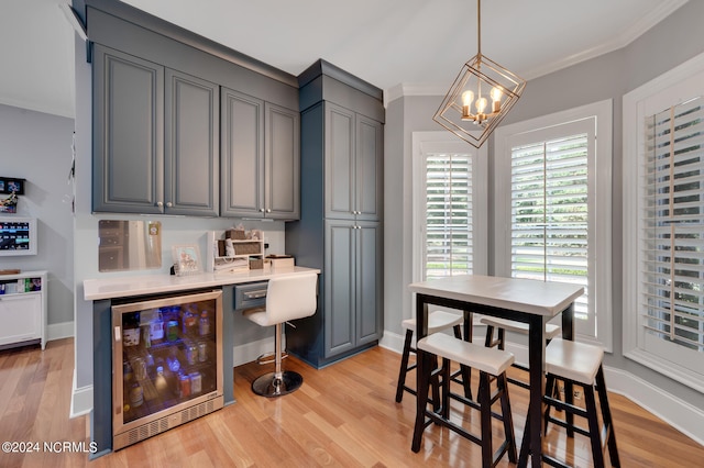 kitchen featuring gray cabinetry, ornamental molding, light hardwood / wood-style flooring, decorative light fixtures, and wine cooler