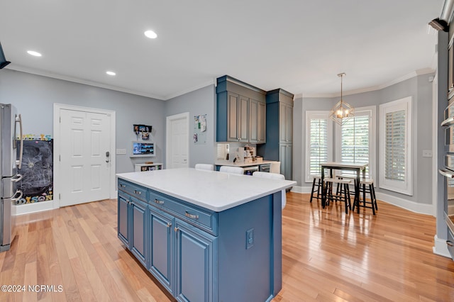 kitchen featuring blue cabinets, crown molding, a kitchen island, pendant lighting, and light wood-type flooring