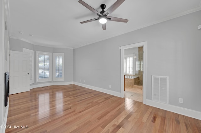 spare room featuring plenty of natural light, light wood-type flooring, and ornamental molding