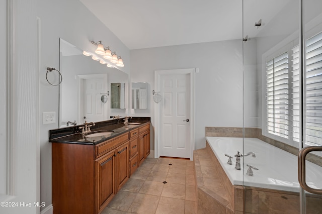 bathroom with tiled bath, tile patterned flooring, vanity, and a healthy amount of sunlight