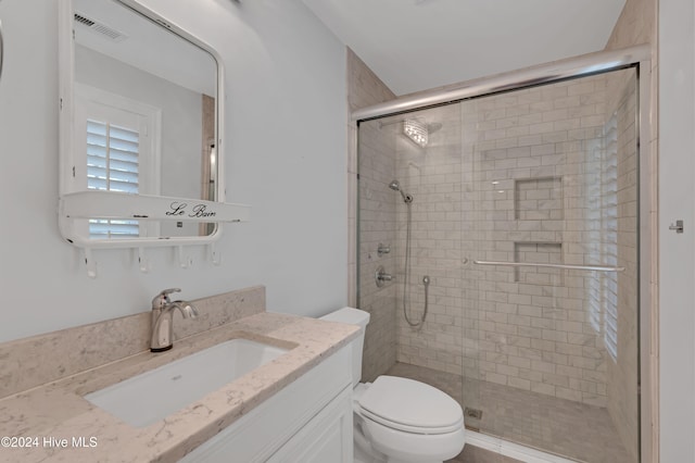 bathroom featuring vanity, toilet, and an enclosed shower