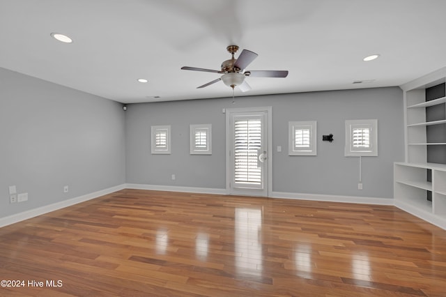 unfurnished living room featuring light wood-type flooring, built in features, and ceiling fan