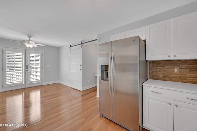 kitchen featuring a barn door, stainless steel fridge with ice dispenser, white cabinetry, and light hardwood / wood-style flooring