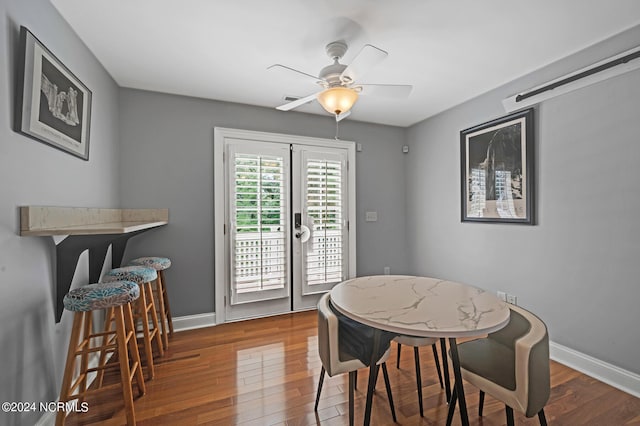 dining space with a barn door, wood-type flooring, and ceiling fan