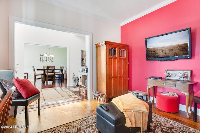 sitting room featuring crown molding, a notable chandelier, and hardwood / wood-style flooring