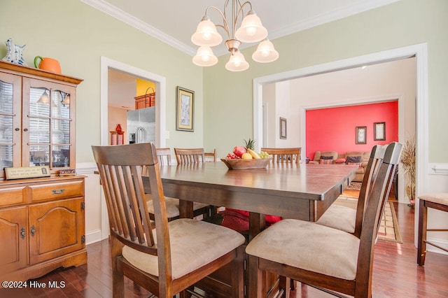 dining space with dark hardwood / wood-style flooring, ornamental molding, and a notable chandelier