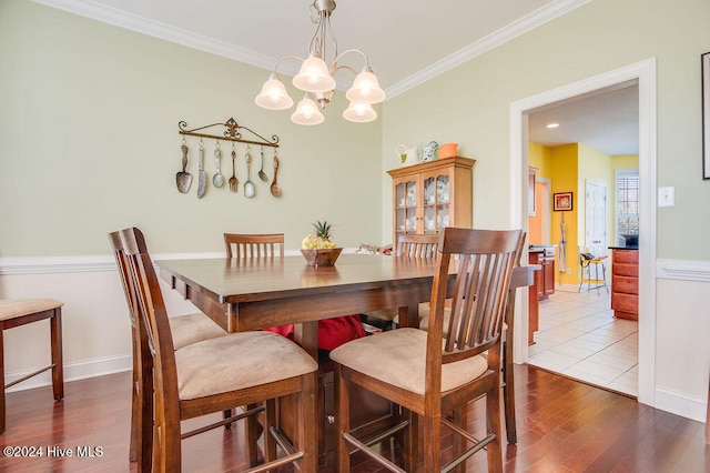 dining space with hardwood / wood-style floors, a chandelier, and ornamental molding