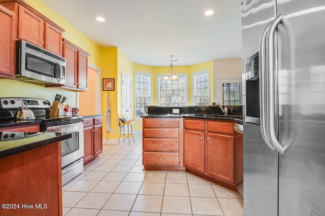 kitchen with sink, light tile patterned floors, appliances with stainless steel finishes, decorative light fixtures, and a chandelier