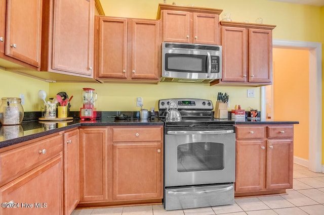 kitchen featuring dark stone countertops, light tile patterned flooring, and stainless steel appliances