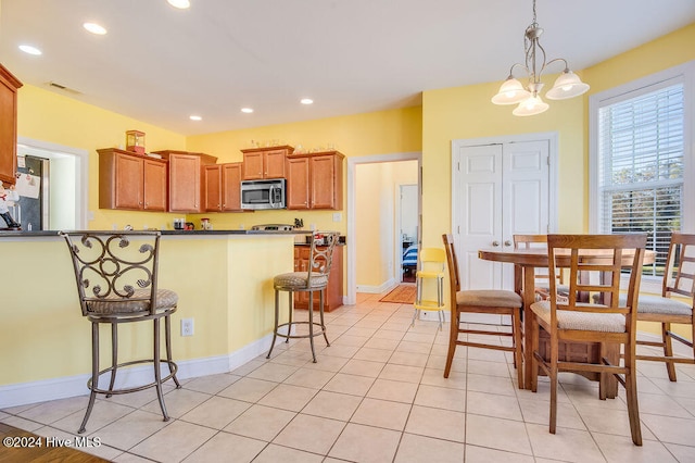 kitchen with a breakfast bar, light tile patterned floors, decorative light fixtures, and a notable chandelier