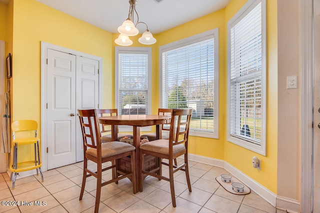 dining space with light tile patterned floors, a healthy amount of sunlight, and a notable chandelier