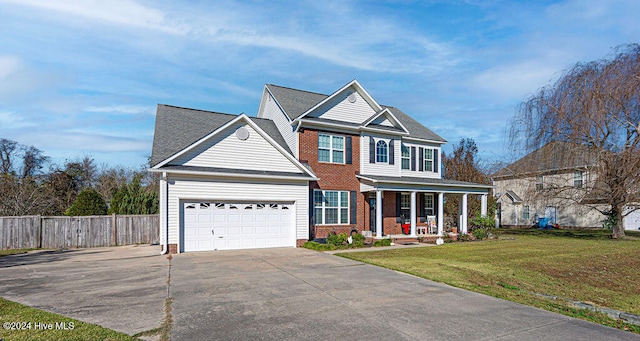 view of front of property featuring a garage, covered porch, and a front yard