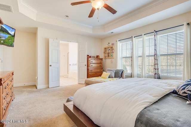 carpeted bedroom featuring a tray ceiling, connected bathroom, ceiling fan, and crown molding